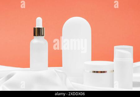 Creme, Maske, Lotion und Serum für Gesichts- und Körperpflege. Kosmetische Produkte auf einem Podium aus Seidengewebe. Stockfoto