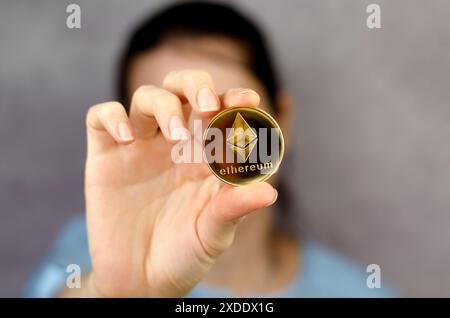 Ethereum-Münze in einer weiblichen Nahaufnahme. Nicht erkennbare Frau, die ethereum vor ihrem Gesicht hält. Kryptowährung - Ukraine, Izmail, 17.03.2022 Stockfoto