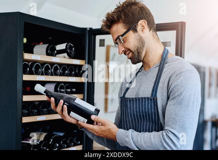 Mann, Restaurant und Kellner im Weinkeller mit einem Lächeln für Service, Gastfreundschaft und Professionalität. Mitarbeiter, Alkohol und glücklich oder zufrieden in der Weinkellerei Stockfoto