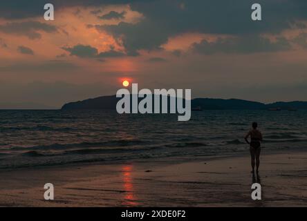 Ein Bild einer Frau, die den Sonnenuntergang am Strand von Ao Nang beobachtet. Stockfoto