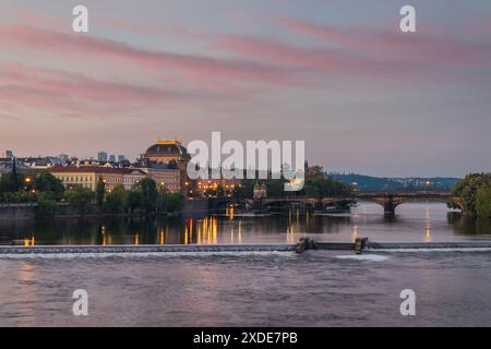 Uferpromenade der Moldau in Prag mit dem Gebäude des Nationaltheaters, beleuchtet durch künstliche Beleuchtung am frühen Morgen vor Sonnenuntergang Stockfoto