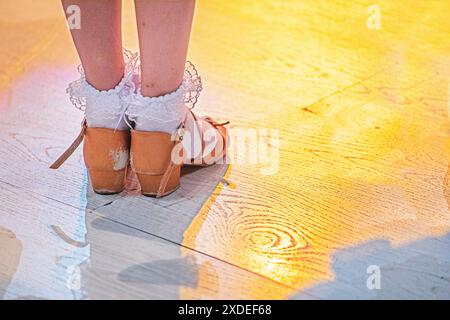 Mädchenfüße in Tanzschuhen stehen vor dem Turnier auf dem Boden. Nicht-olympischer Sport Stockfoto