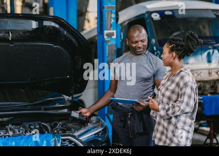 Mechaniker, der mit Frauen spricht, Kunden informieren, erklären Fahrzeugproblem, Service-Details in der Garage. Stockfoto