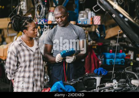 Mechaniker im Gespräch mit dem Kunden informieren, erklären, dass die Klimaanlage zu wenig Flüssigkeit vorhanden ist, und Details zum Service in der Garage. Stockfoto