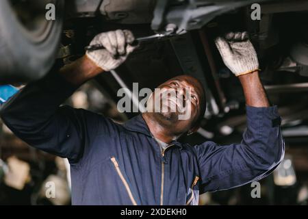 Mechaniker arbeiten Reparatur Fahrzeug im Fahrzeug Service. Professioneller Mitarbeiter mit Ratsche unter dem Fahrzeug in der Werkstatt Stockfoto