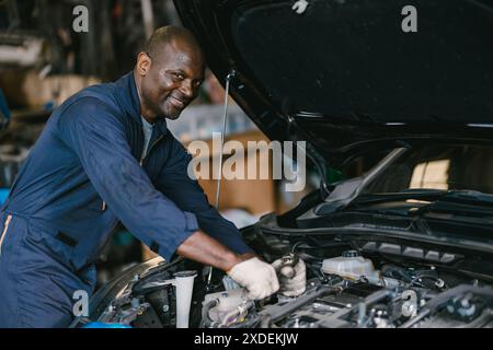 Afrikanischer schwarzer Mann Autoservice Mechaniker, der glücklich lächelnd in der Werkstatt arbeitet. Stockfoto
