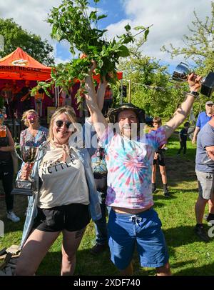 Waytown, Dorset, Großbritannien. Juni 2024. Die Damen- und Herren-Champions Bethan Hodges und Tom Wheeler mit ihren Trophäen bei der jährlichen Nettle Eating Championship auf der Dorset Nectar Cider Farm in Waytown in Dorset. Ziel des Wettbewerbs ist es, die Blätter von vielen zwei Fuß großen Brennnesselstielen so schnell wie möglich in 30 Minuten zu essen, die von Cidre heruntergespült werden. Tom aß 116 Meter Brennessel. Bildnachweis: Graham Hunt/Alamy Live News Stockfoto