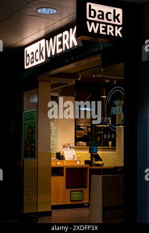 Koblenz, Deutschland - 19. Februar 2024: Blick auf den Eingang einer Backwerk Bäckerei bei Nacht. Das Geschäft ist von innen beleuchtet und ein Schild mit dem Geschäft Stockfoto