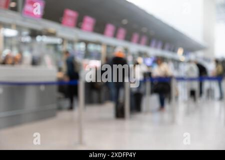 Eine verschwommene Darstellung eines belebten Check-in-Schalters am Flughafen mit zahlreichen Reisenden, die in der Schlange stehen, Gepäckwagen schieben und mit der Airline interagieren Stockfoto