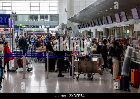 Frankfurt Airport, Deutschland - 19. Februar 2024: Das Bild zeigt einen belebten Check-in-Schalter am Flughafen, an dem zahlreiche Reisende anstehen und drängen Stockfoto