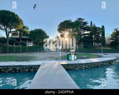 Gardasee, Peschiera del Garda, Italien, Europa, siehe, Wasser, Strand, Sonnenuntergang, Natur, Erholung, Tourismus, Urlaub, Sommer, Landschaft, kristallklares Wasser, Spaziergang, Promenade, Pier, Bänke, Grünflächen, Bäume, Freizeit, Aussicht, Seeufer, Entspannung, historische Stadt, Sehenswürdigkeiten, Unterkunft, Ferien, Urlaubsziel, Norditalien, Sonnenstrahlen, Naturparadies, malerische Umgebung, Reisefotografie, Drohnenaufnahme, Klimawandel, Wasserqualität, nachhaltiger Tourismus, Umweltschutz, Anwohnerproteste, Verkehr, Tourismusindustrie, lokale Wirtschaft, Wasserspiegel, Mülltrennung, Nac Stockfoto