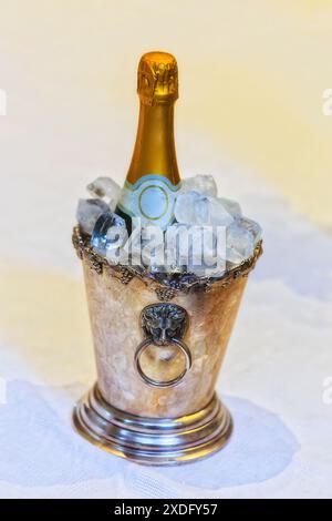 Eine Flasche Sekt im Eiskübel, serviert auf weißem Tischtuch. Stockfoto