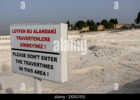 Ein Schild mit der Aufschrift Bitte betreten Sie die Travertine in dieser Gegend nicht, aufgenommen an den wunderschönen weißen Travertinen von Pamukkale in Türkiye an einem sonnigen Tag. Stockfoto