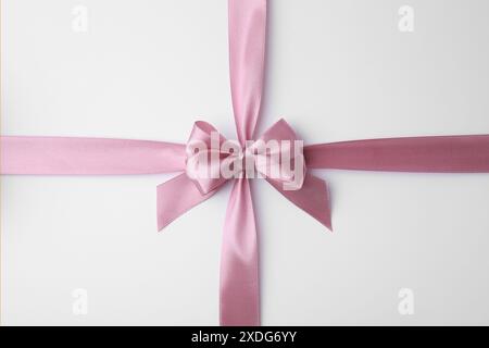 Pinkes Satinband mit Schleife auf weißem Hintergrund, Draufsicht Stockfoto