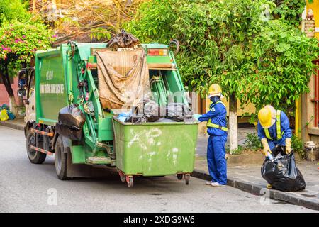 Hoi an (Hoian), Vietnam - 12. April 2018: Müllsammler laden Müll von Hand. Müllwagen in der alten Straße von Hoi an Alte Town am Morgen. Stockfoto