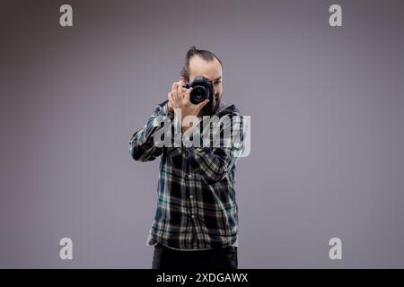 Selbstbewusstes Fotografieren mit professioneller Kamera im Studio. Passionierter Hobbykünstler zeigt Kreativität und Können Stockfoto