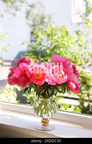 Wunderschöne rosafarbene Pfingstrosen in Vase auf Fensterbank Stockfoto