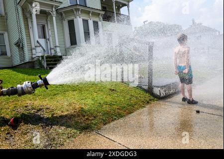 Kinder tummeln sich während einer Hitzewelle im Sprühnebel eines Hydranten, der von der Feuerwehr im Barre, VT, USA, geöffnet wurde. Stockfoto