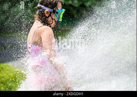 Kinder tummeln sich während einer Hitzewelle im Sprühnebel eines Hydranten, der von der Feuerwehr im Barre, VT, USA, geöffnet wurde. Stockfoto