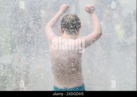 Kinder tummeln sich während einer Hitzewelle im Sprühnebel eines Hydranten, der von der Feuerwehr im Barre, VT, USA, geöffnet wurde. Stockfoto