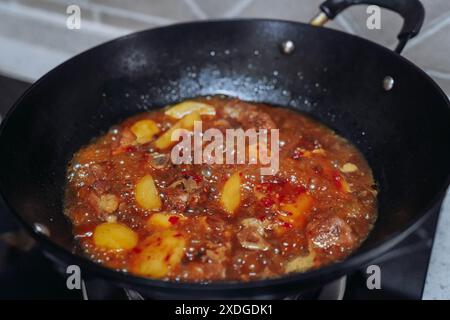 Kartoffeln gebratene Schweinerippchen werden in einem Eisenkopf auf dem Herd nach Sichuan gedünstet. Stockfoto