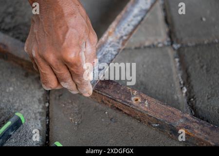 Nahaufnahme einer Person, die an einem rostigen Metallrahmen arbeitet, möglicherweise repariert oder montiert. Die Hand hält ein Werkzeug und es gibt ein sichtbares Schild Stockfoto