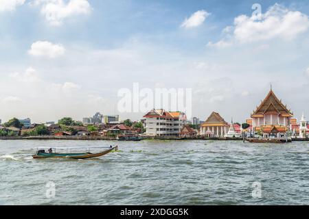 Traditionelles Segeln auf dem Chao Phraya Fluss in Bangkok, Thailand. Wat Kalayanamitr ist am Ufer sichtbar. Stockfoto