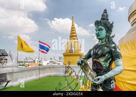 Buddhistische Statue im Tempel Wat Saket auf dem Goldenen Berg. Die Flagge des Königreichs Thailand, die über Bangkok flattert, ist im Hintergrund sichtbar. Stockfoto