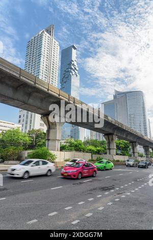 Malerischer Blick auf die Sathon Road und das Viadukt der BTS Silom Line in Bangkok, Thailand. Wolkenkratzer sind auf blauem Himmel zu sehen. Tagesverkehr von Bangkok. Stockfoto