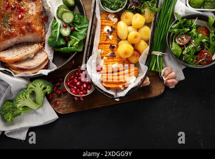 Gebratener Schinken mit Gemüse, Brot und frischem Salat auf schwarzem Hintergrund. Draufsicht. Stockfoto