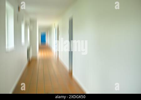 Langer Gang und Fenster mit Bewegungsunschärfe im Innenraum für Gehweg, horizontal und Tür am Ende für den Zugang zum Klassenzimmer oder Raum. Krankenhaus, Schule und Stockfoto