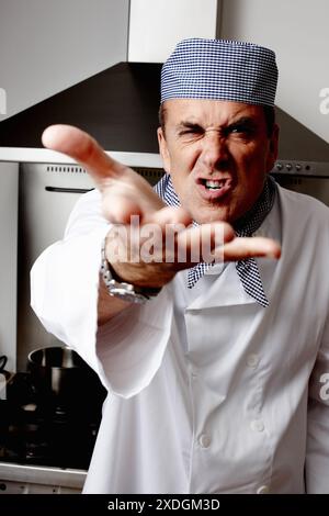 Mann, wütend und Koch mit Schreien in der Küche für Kochen, Gastfreundschaft oder kulinarischen Profi. Reifer Mensch, wütend und Lebensmittelindustrie im Hotel Stockfoto