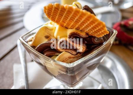 Gemischte Vanille- und Schokoladeneis mit Waffel in einer Glasschale auf dem Tisch, Nahaufnahme. Stockfoto