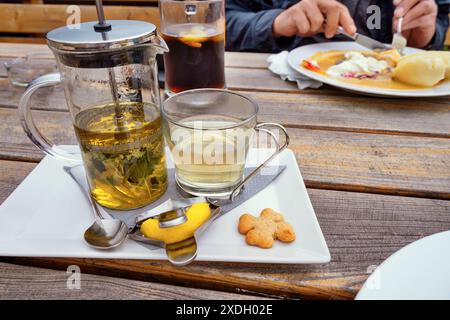 Restauranttisch mit Kräutertee auf Teller und Mahlzeit auf Teller und Männerhänden essen Essen. Essen. Stockfoto