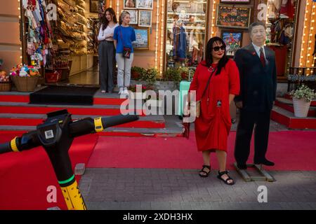 Moskau, Russland. Juni 2024. Eine Frau macht ein Foto mit einem Pappbild, das den chinesischen Präsidenten Xi Jinping in der Nähe des Eingangs eines Souvenirshops in der touristischen Arbat-Straße in der Moskauer Innenstadt zeigt Stockfoto