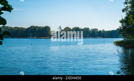 Vilnius, Litauen, 29. September 2023, Segelboote vor Anker in der Nähe der Ruinen der Burg trakai im stillen Seewasser neben grüner Waldlandschaft Stockfoto