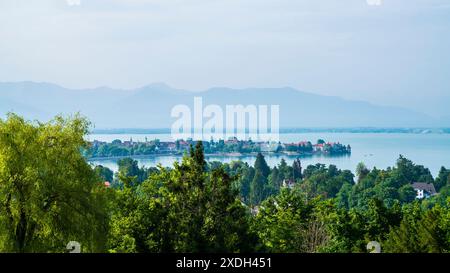 Deutschland, Lindau Inselhäuser, Gebäude, Leuchtturm und grüne Bäume umgeben von stillen bodensee-Wasser früh am Morgen nach Sonnenaufgang, aeri Stockfoto