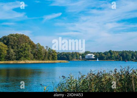 Vilnius, Litauen, 29. September 2023, wunderschönes weißes Haus an den Ruinen der Burg trakai, umgeben von grünem Wald und Seewasser im Sommer Stockfoto