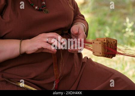 Frau webt gemusterte Stoffe von Hand mit einem Holztablettenwerkzeug. Stockfoto