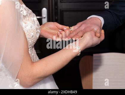 Zugeschnittene Ansicht von Braut und Bräutigam, Braut, die Ehering auf den Finger des Bräutigams legt Stockfoto