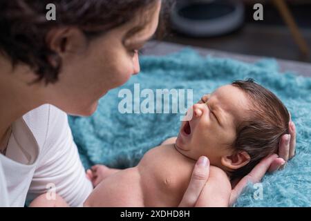 Eine liebevolle Mutter kümmert sich um ihr neugeborenes Baby. Porträt einer Mutter, die ein weinendes Baby in den Armen hält. Mutter umarmt ihren kleinen Sohn. Stockfoto