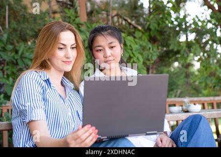 Glückliches junges multiethnisches Paar, das Zeit zusammen im Park verbringt und mit Laptop lernt Stockfoto