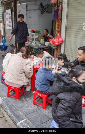 Hanoi, Vietnam - 9. Februar 2024: Diners sitzen in einem Street Food Stall in Hanois Altstadt Stockfoto