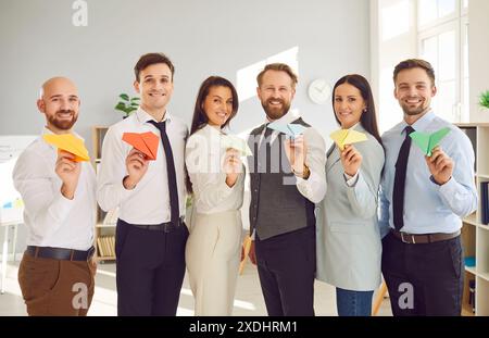 Team von glücklichen, selbstbewussten Geschäftsleuten, die gemeinsam Papierflugzeuge im Büro fliegen Stockfoto