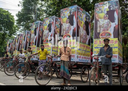 Dhaka, Bangladesch. Juni 2024. Ein Rikscha-Puller und Aktivisten der regierenden Awami-Liga posieren für ein Bild mit den Spruchbändern während der großen Kundgebung. Die Awami League Party organisierte eine Kundgebung, um das Platin-Jubiläum der Partei zu feiern, an der Tausende von Menschen teilnahmen. Quelle: SOPA Images Limited/Alamy Live News Stockfoto