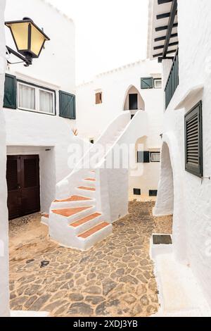Die wunderschöne Stadt Binibeca auf Menorca. Enge Gassen und weiße Wände von Häusern mit Holzelementen, mediterrane Architektur in Spanien Stockfoto