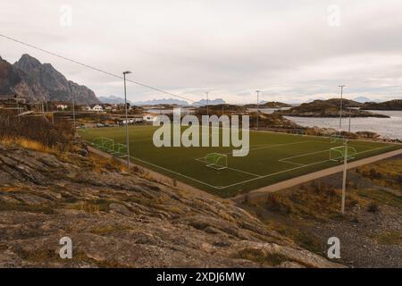 Blick auf das Henningsvaer Fußballstadion in Norwegen mit dem Meer und den Inseln. Fußballfeld auf den Lofoten, umgeben von Felsen und Steinen Stockfoto