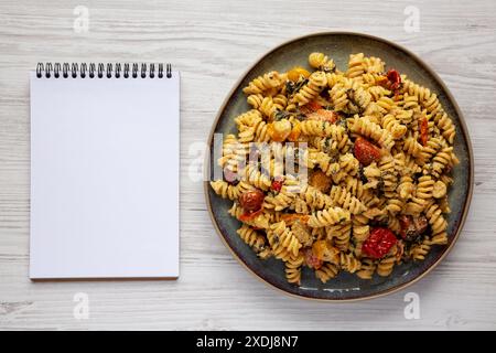 Hausgemachte gebackene Boursin-Pasta auf einem Teller, leerer Notizblock, Draufsicht. Flache Lage, über Kopf, von oben. Stockfoto