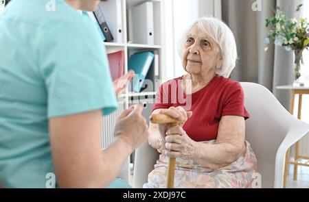 Medizinische Mitarbeiterin hält die Hand einer älteren Frau und beruhigt sie Stockfoto