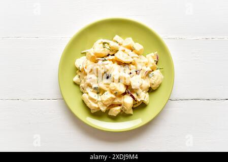 Hausgemachter Kartoffelsalat mit Ei, Gurke, Zwiebeln mit Mayonnaise und Joghurtdressing auf grüner Platte auf weißem hölzernem Hintergrund. Draufsicht, flach Stockfoto